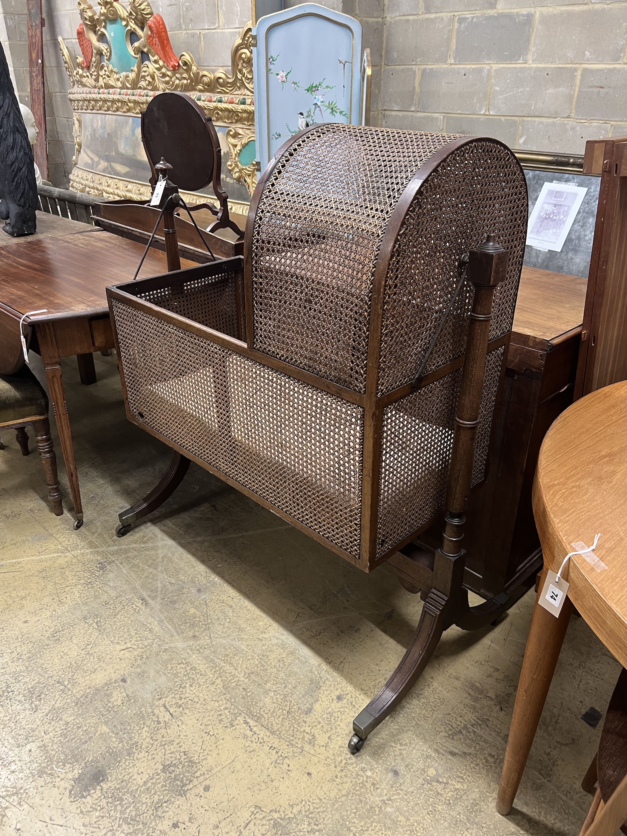 A Regency caned mahogany rocking crib, length 100cm, height 123cm
